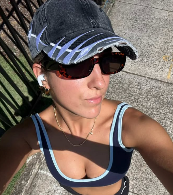 Girl wearing a cap and sunglasses outdoors on a sunny day